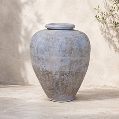 Large textured gray urn on a wooden surface with a neutral background