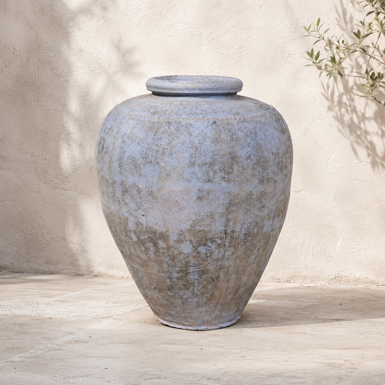 Large textured gray urn on a wooden surface with a neutral background