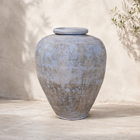 Large textured gray urn on a wooden surface with a neutral background