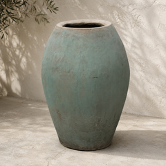 Large textured blue-green ceramic vase on a neutral background
