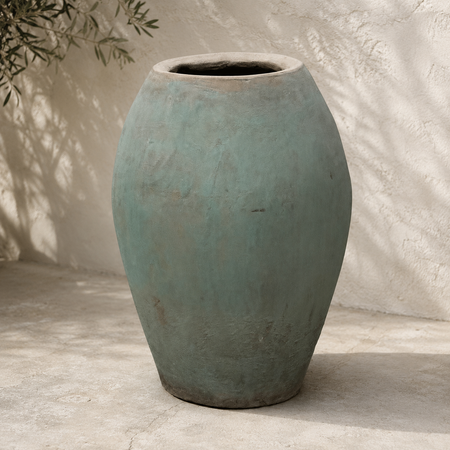 Large textured blue-green ceramic vase on a neutral background