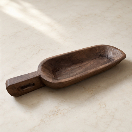 Wooden scoop on a light beige surface