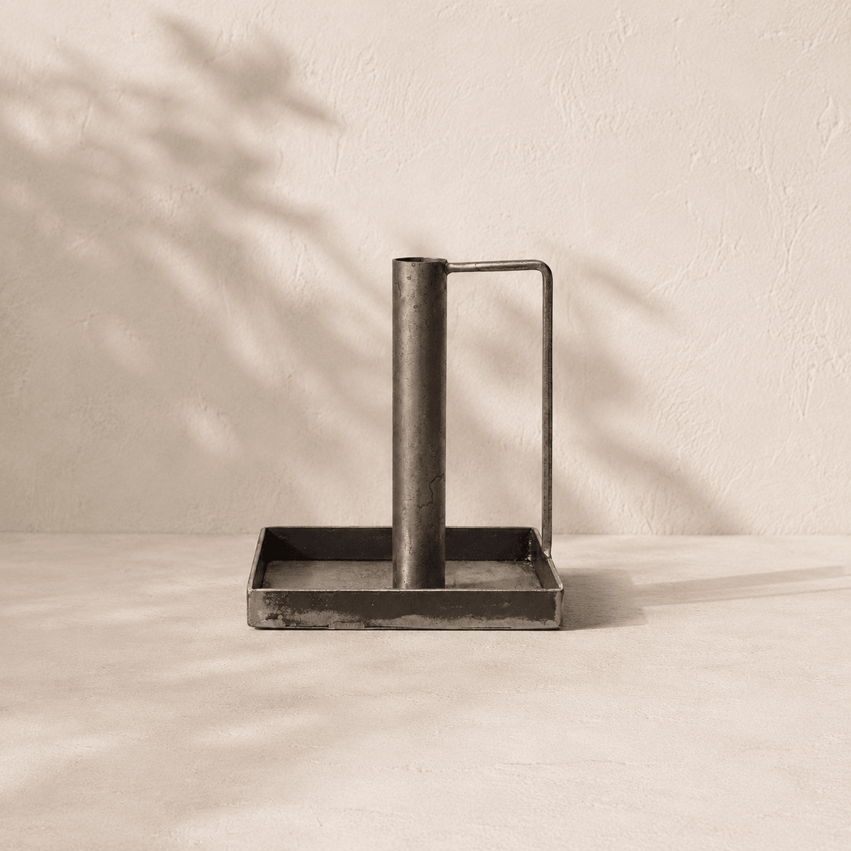 Metal  Forged candlestick with handle and tray on a beige surface with shadow effect