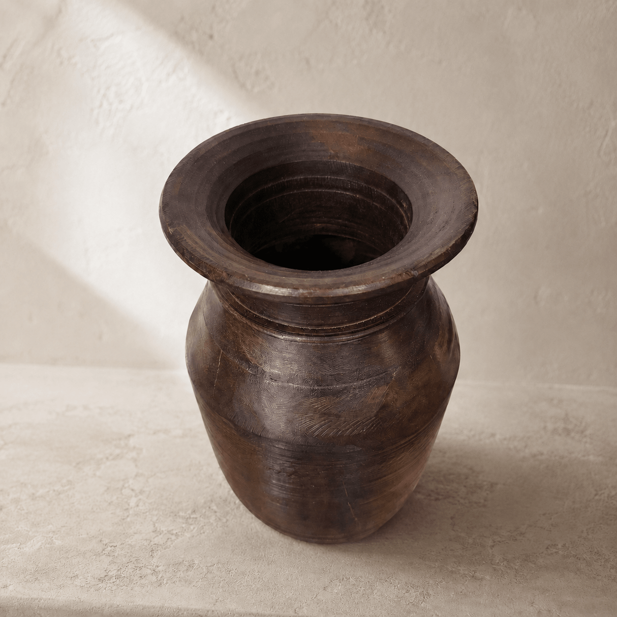 Dark brown wooden vase on a light beige background