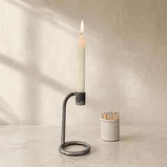 Candle in a holder with matches on a marble surface and beige wall background
