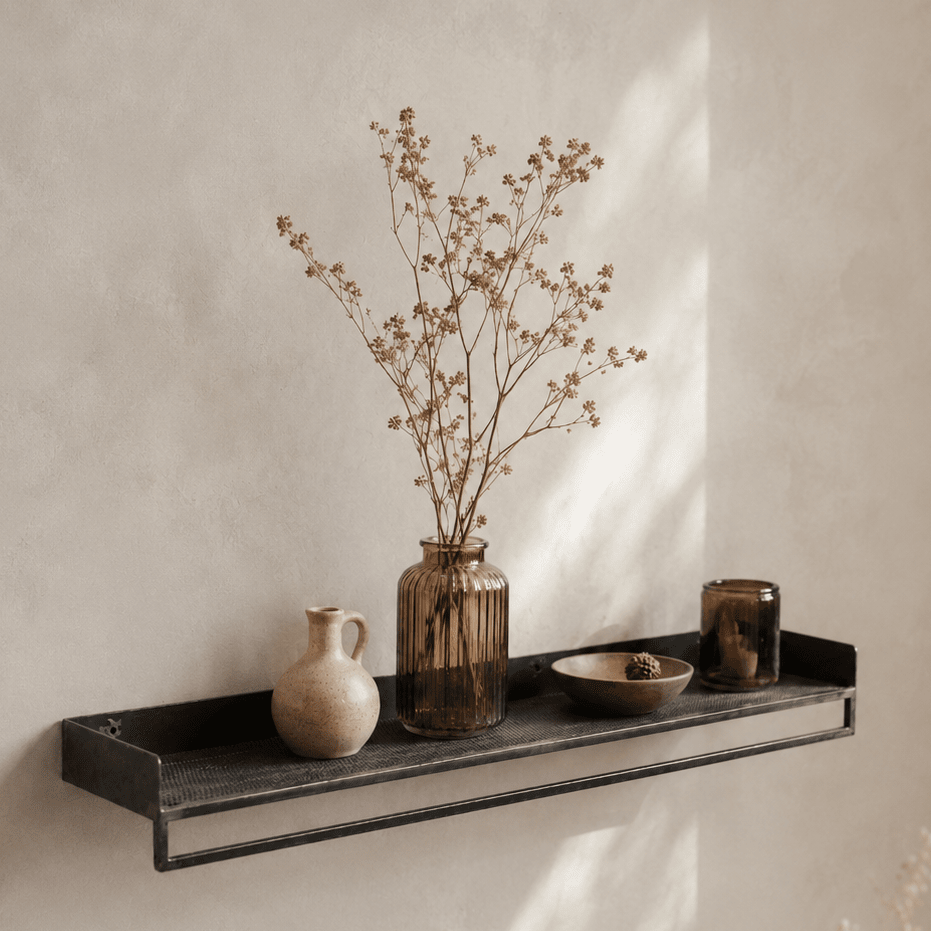 Decorative metal shelf with vases and a bowl against a beige wall