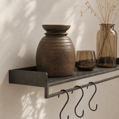 Decorative shelf with a large brown vase, glass, and jar against a neutral wall.