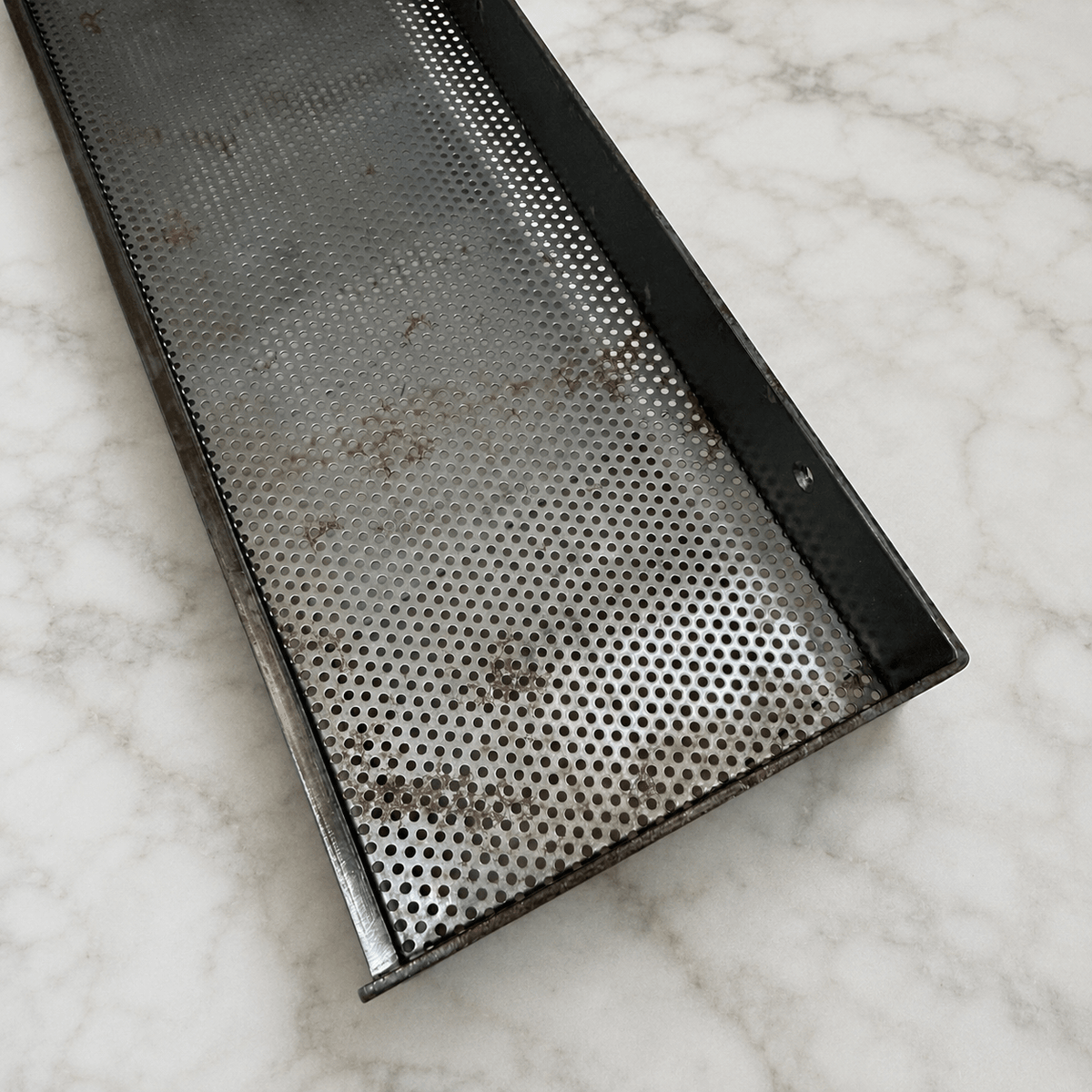 Perforated iron shelf on a marble counter 