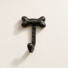 Black bone-shaped wall hook on a light beige background