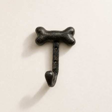 Black bone-shaped wall hook on a light beige background