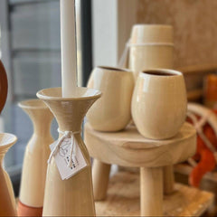 white ceramic candle holder with a white candle on a wooden surface.