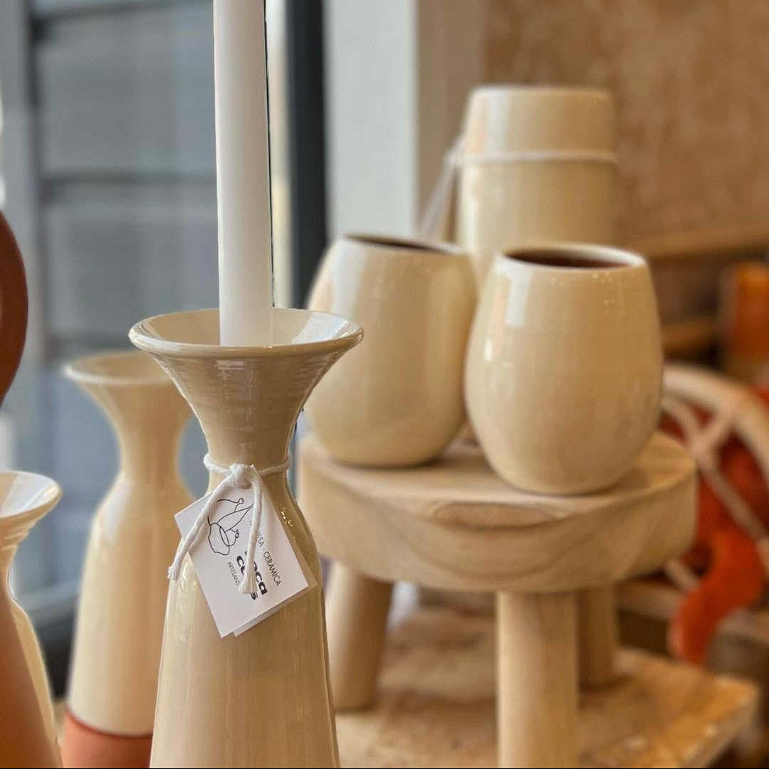 white ceramic candle holder with a white candle on a wooden surface.