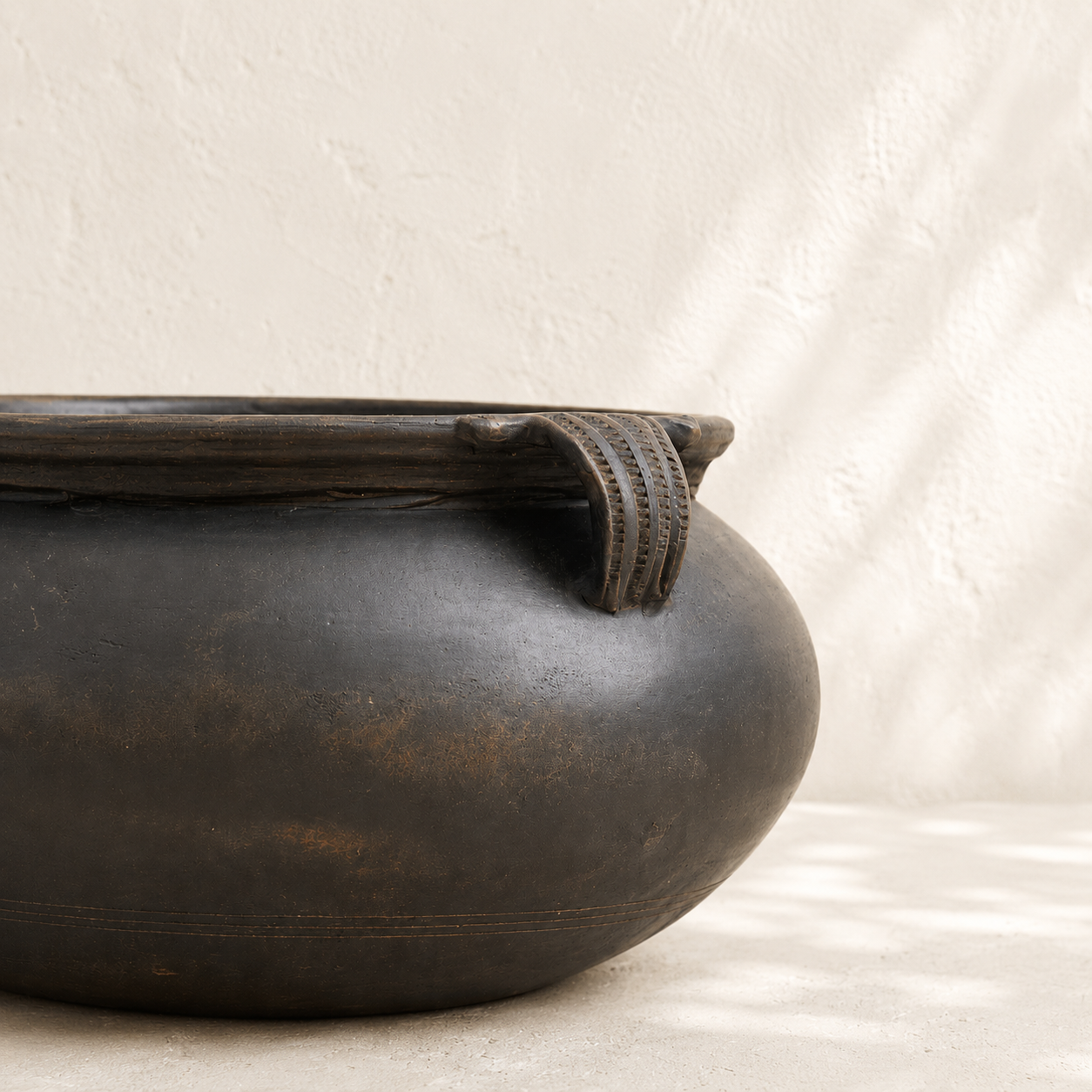 Black ceramic pot with a textured surface on a light background
