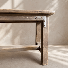 Wooden bench with metal bracket against a neutral background