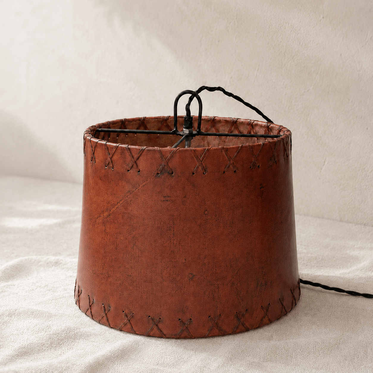 Brown leather lampshade with stitching details on a beige background