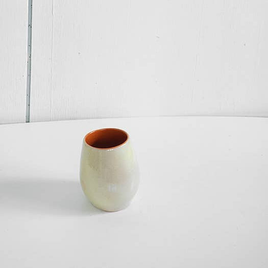 Small ceramic cup with a brown interior on a white background