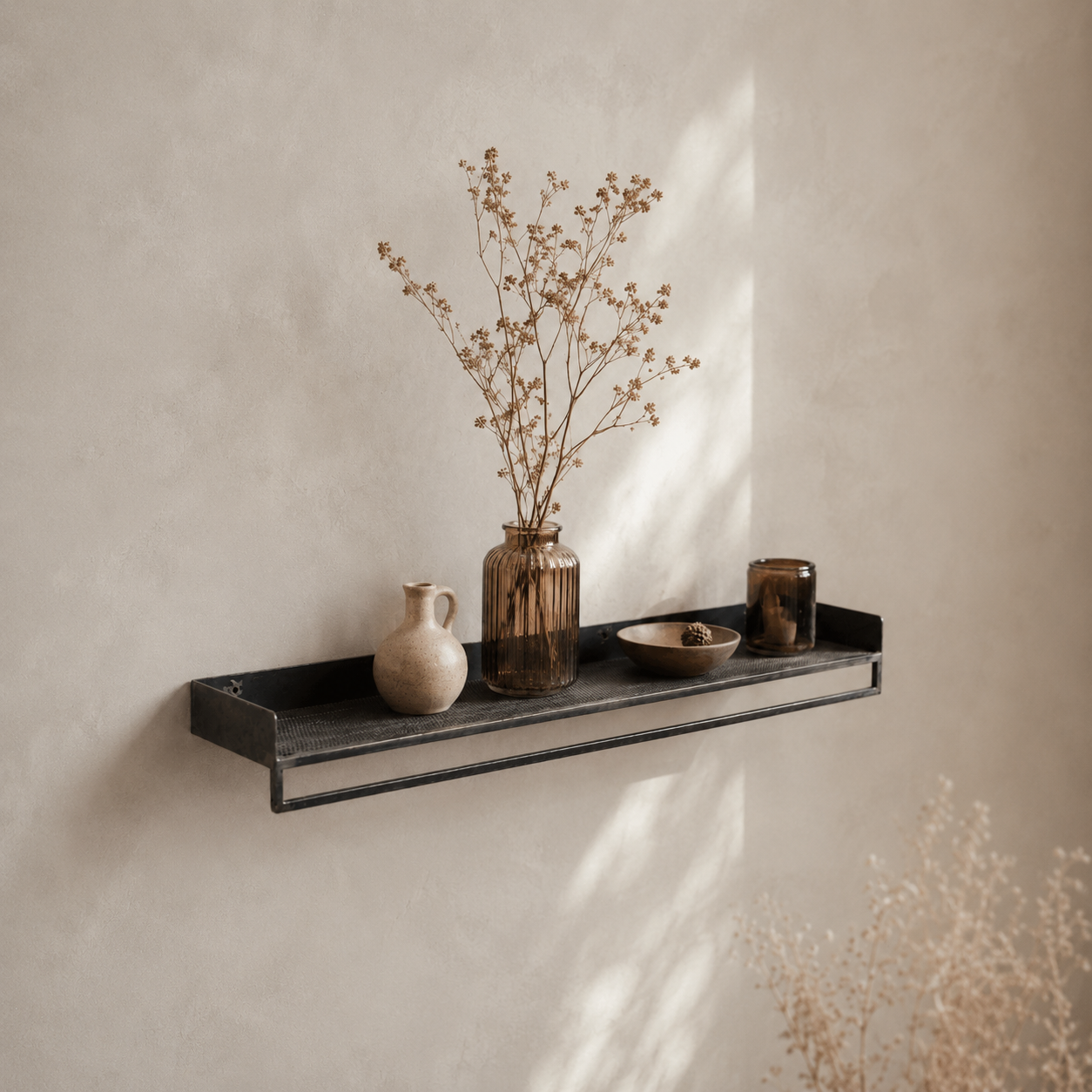 Decorative iron shelf with vases and a bowl against a beige wall