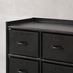 Black metal dresser with multiple drawers against a light gray wall.
