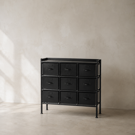 Black dresser with multiple drawers against a beige wall.
