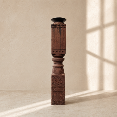 Decorative wooden candle stick with intricate carvings on a beige background