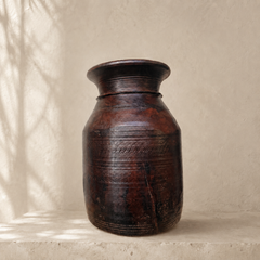 Brown wooden vase on a beige surface with a neutral background