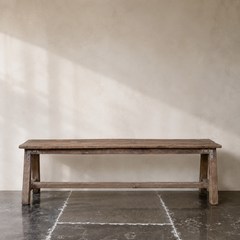 Wooden bench against a plain wall with a light beige color.