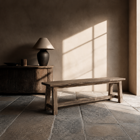 Wooden bench in a room with sunlight streaming through a window, casting shadows on the floor.