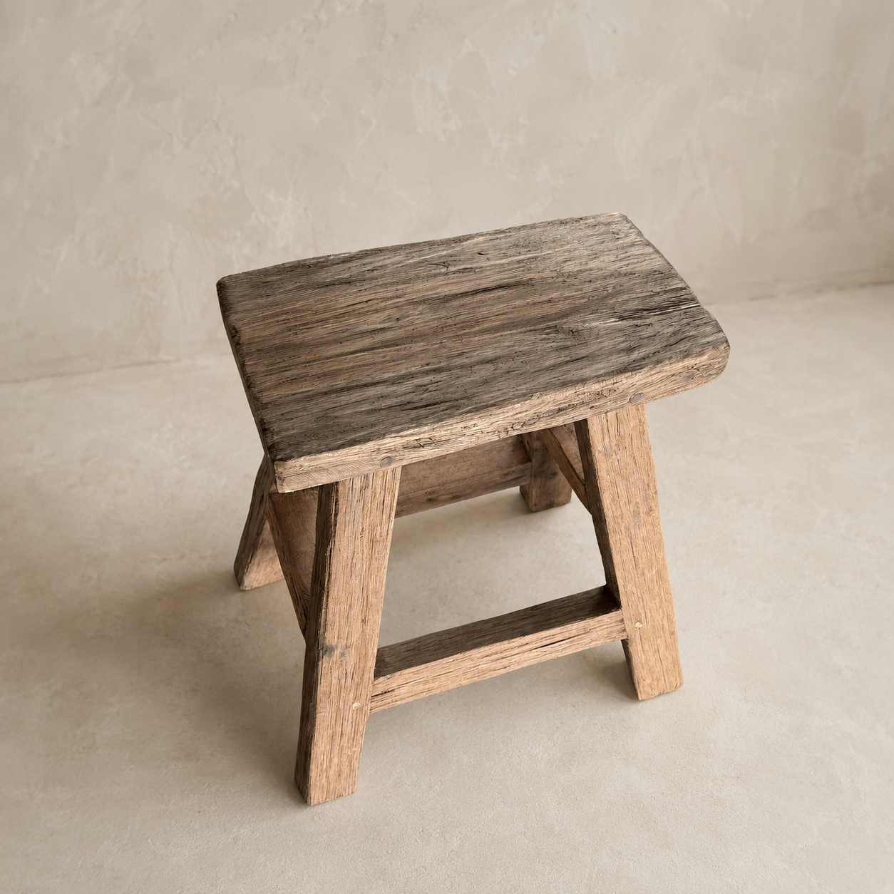 A rustic wooden stool with a weathered dark brown seat and natural wood legs, set against a neutral textured beige background.