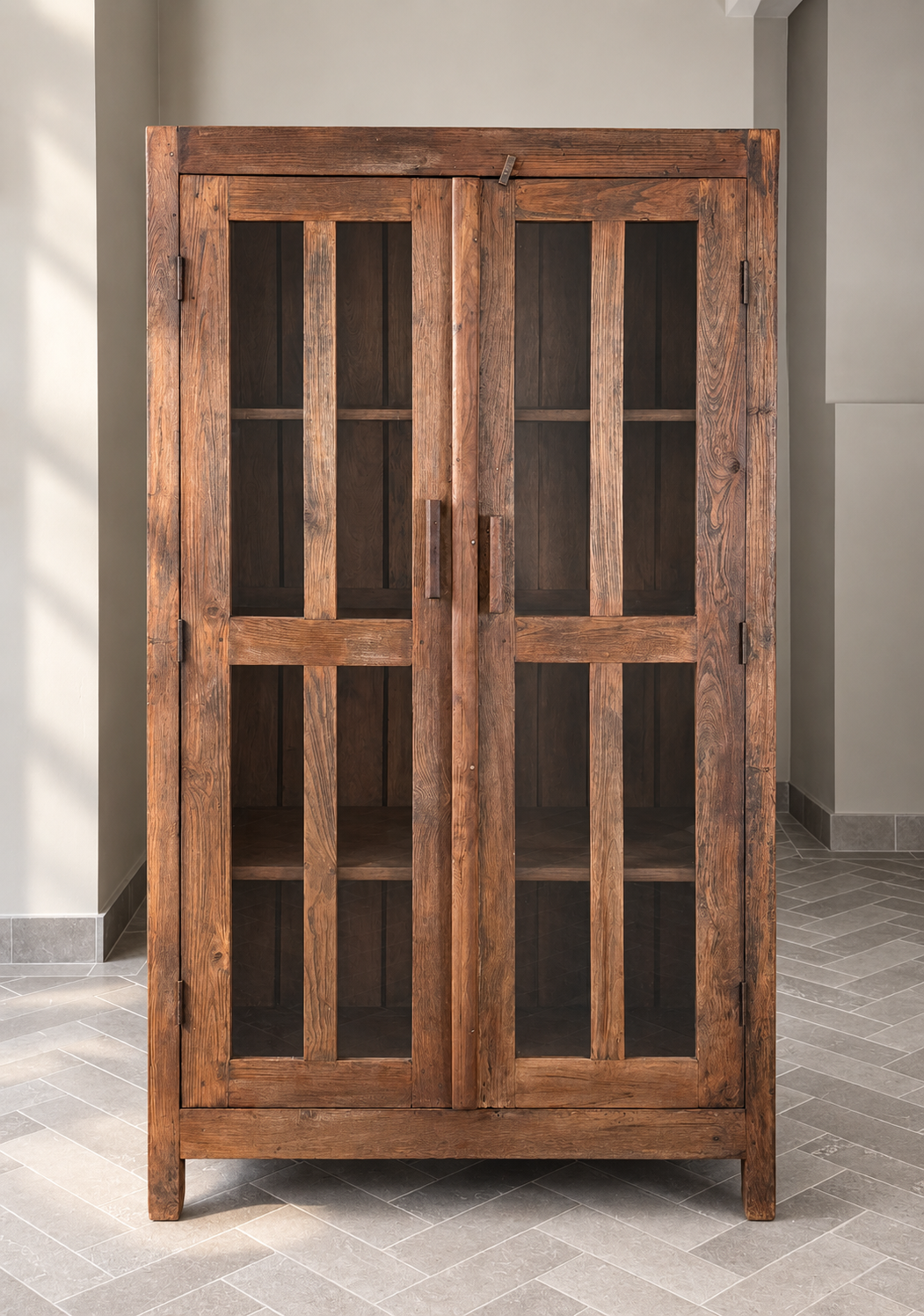 Wooden cabinet with glass doors in a room with gray walls and floor.