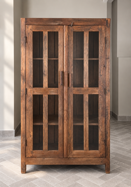 Wooden cabinet with glass doors in a room with gray walls and floor.