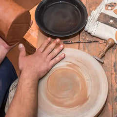 Person working with clay on a pottery wheel in a workshop setting