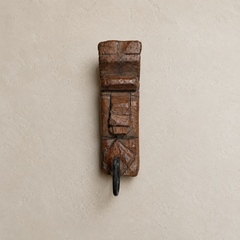 Wooden wall hook with decorative design on a beige wall