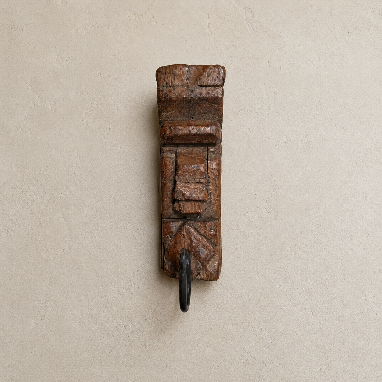 Wooden wall hook with decorative design on a beige wall