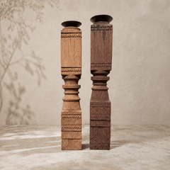 Two tall, intricately carved wooden columns on a neutral background