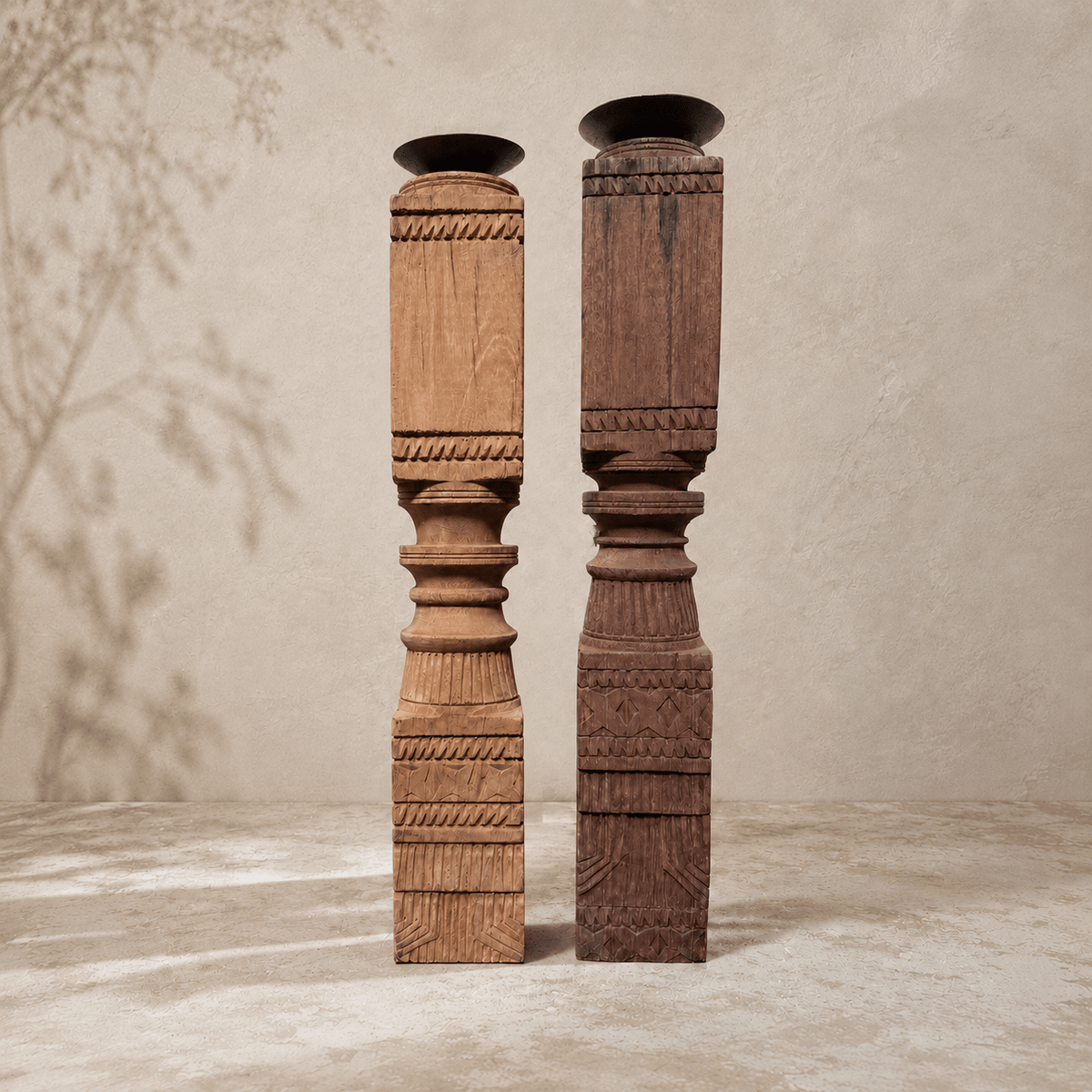 Two tall, intricately carved wooden columns on a neutral background