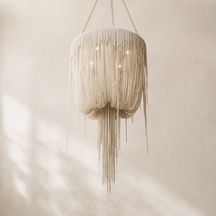 Beige leather fringe chandelier hanging against a neutral background