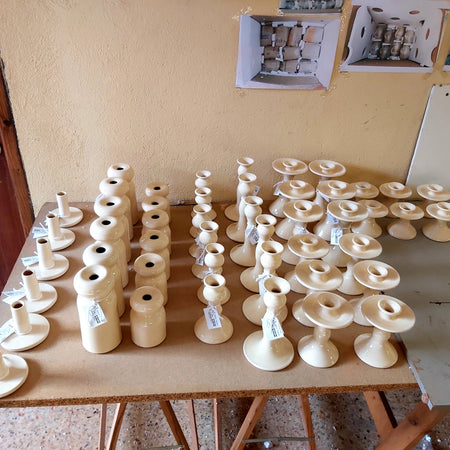 Table with numerous white candle holders in a workshop setting