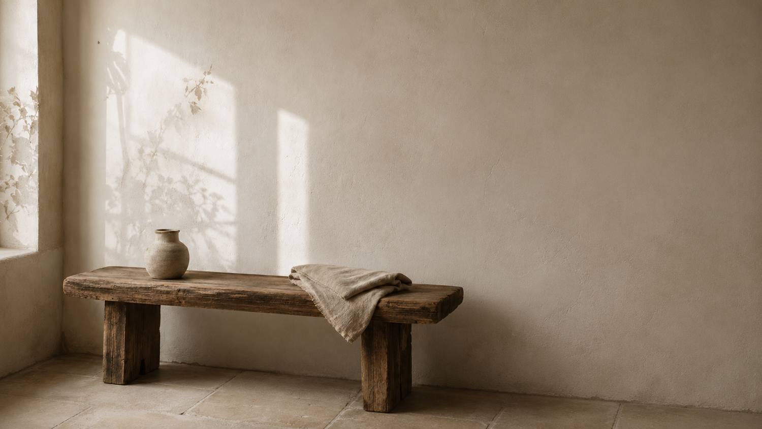 Wooden bench with a vase and towel in a softly lit room.