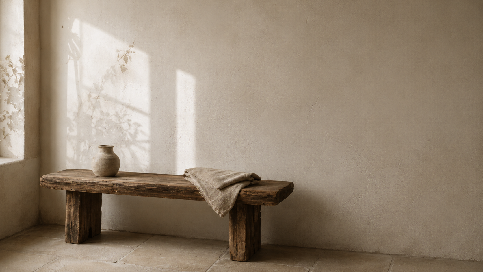 Wooden bench with a vase and towel in a softly lit room.